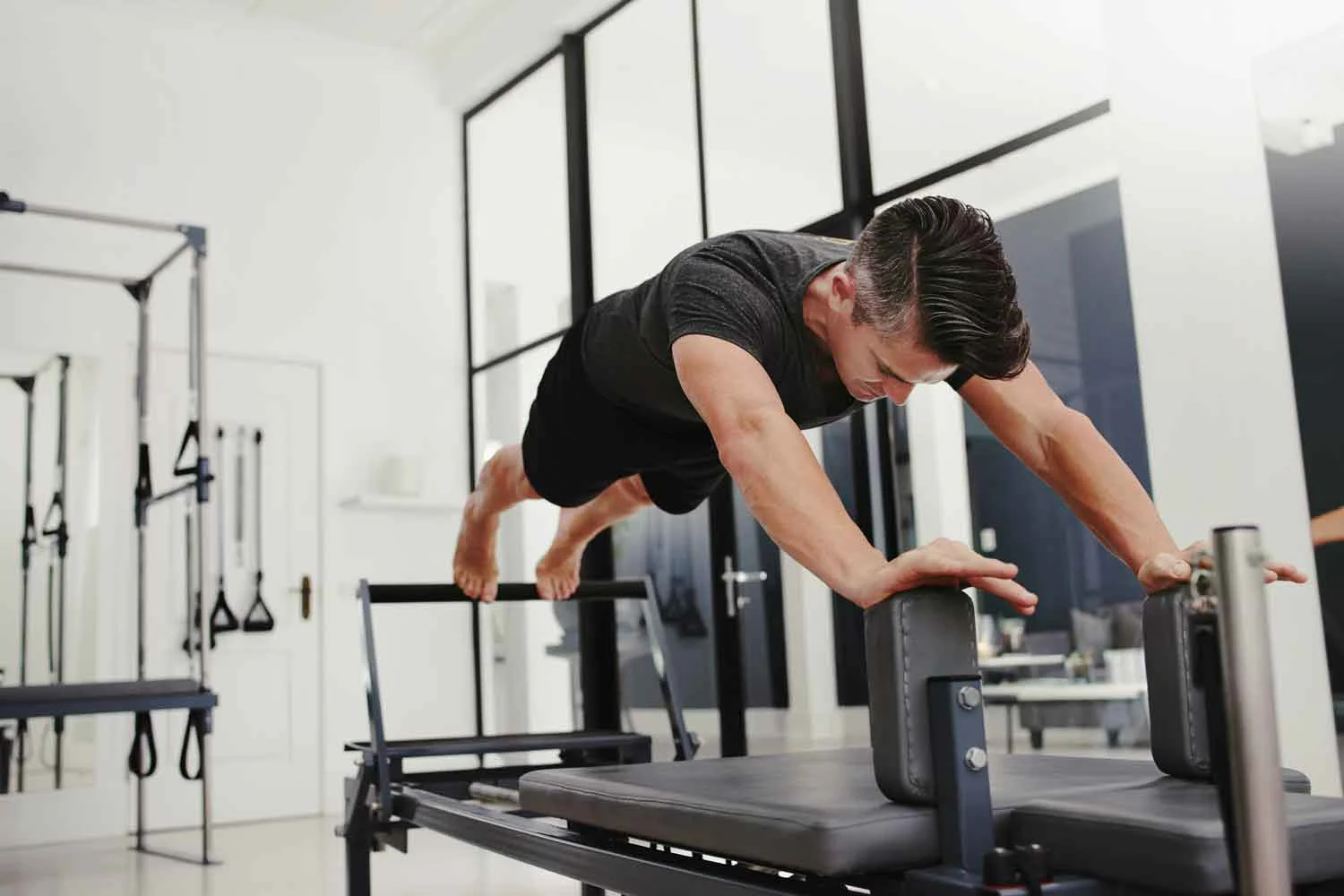 Man performing a plank on the Reformer in a Pilates studio
