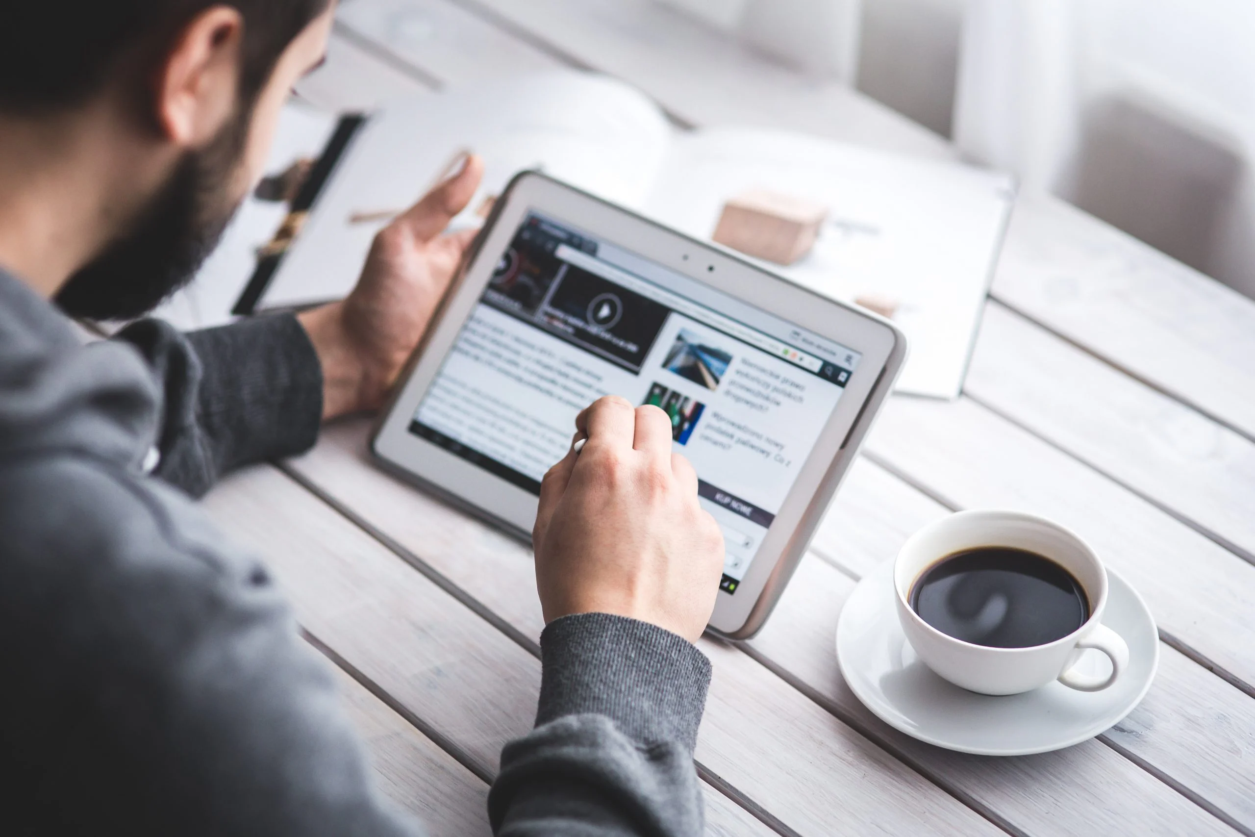 Man reading an article on a tablet with a cup of coffee