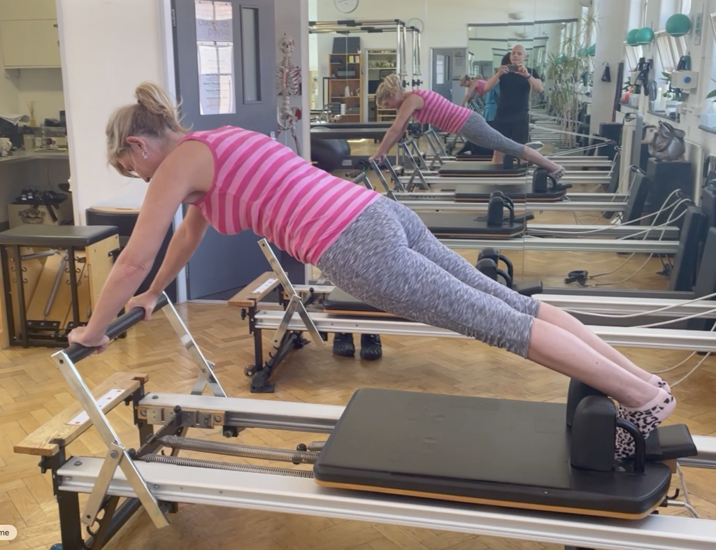 Client holding a controlled plank on the reformer at Applied Pilates, St Albans