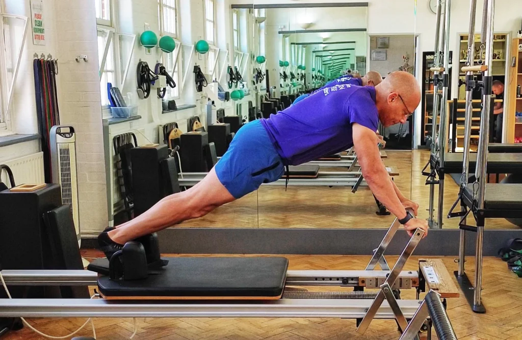 Teejay Sogunro performing a long stretch plank on the Reformer at Applied Pilates, London Colney, St Albans