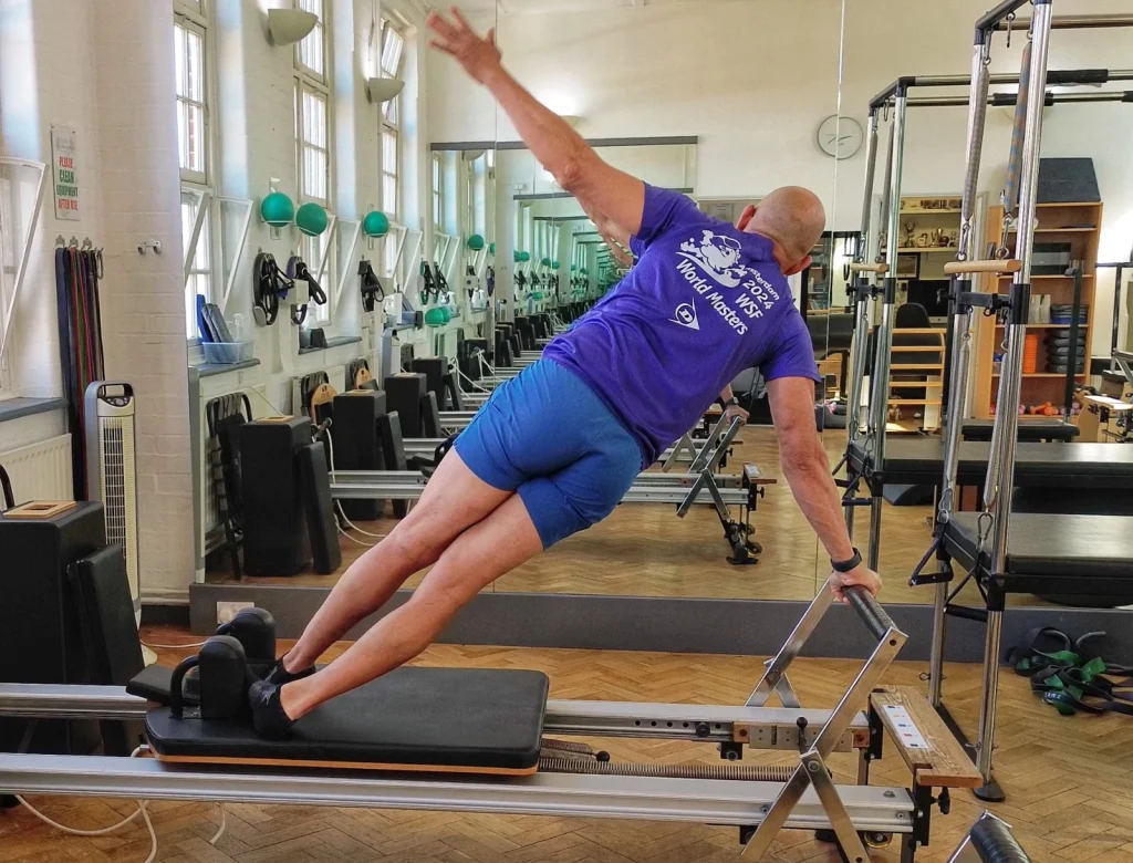 Teejay Sogunro holding a side plank on the Reformer at Applied Pilates, London Colney, St Albans
