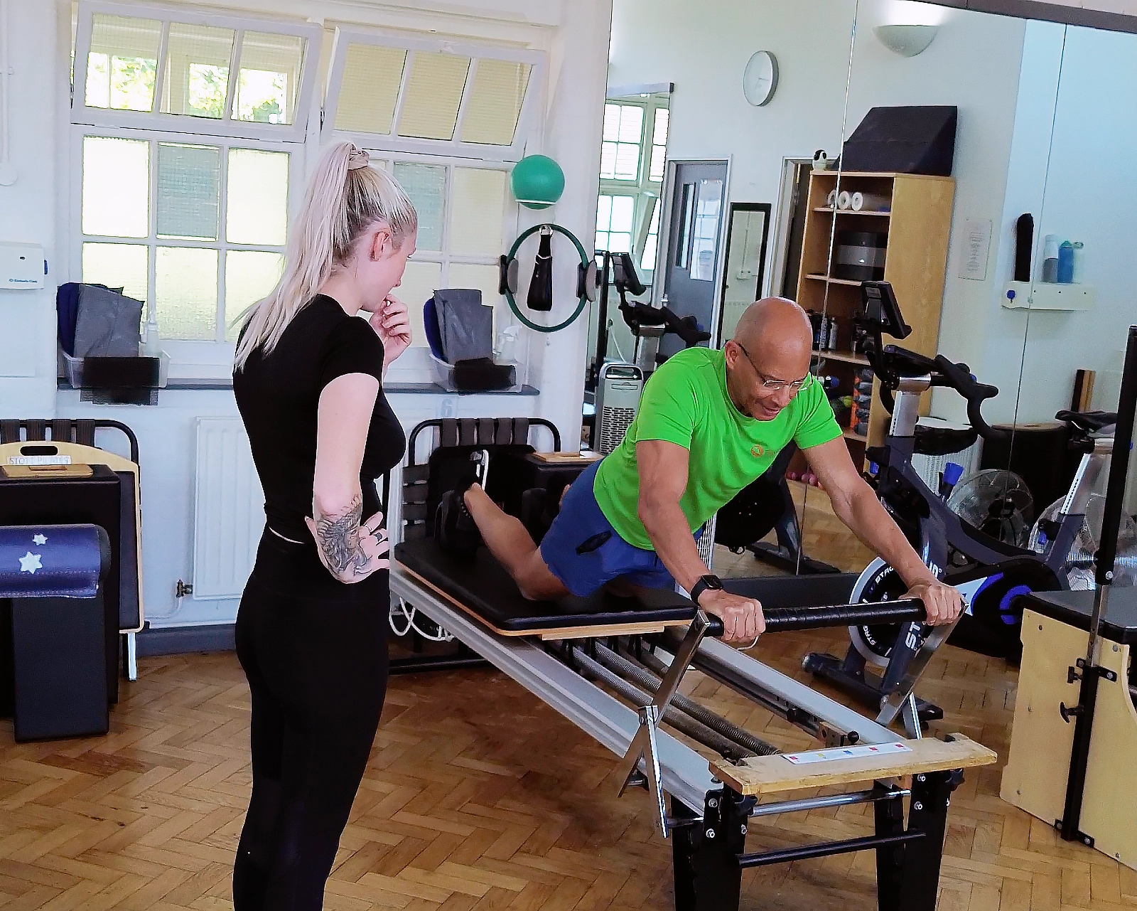 Teejay Sogunro demonstrating a long stretch preparation on the Reformer to a client at Applied Pilates, London Colney, St Albans