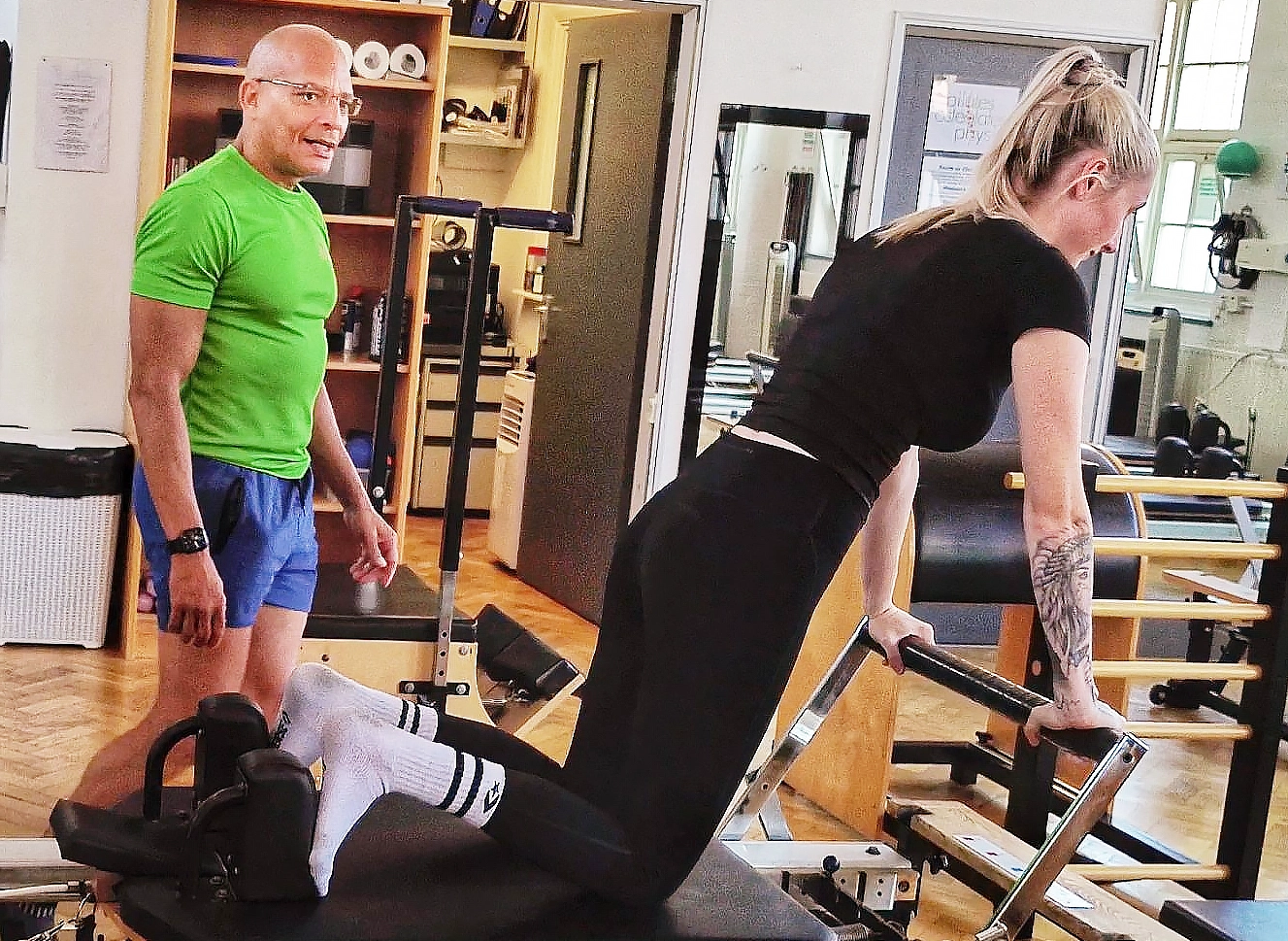 Teejay Sogunro supervising a client through long stretch preparations on the Reformer at Applied Pilates, London Colney, St Albans