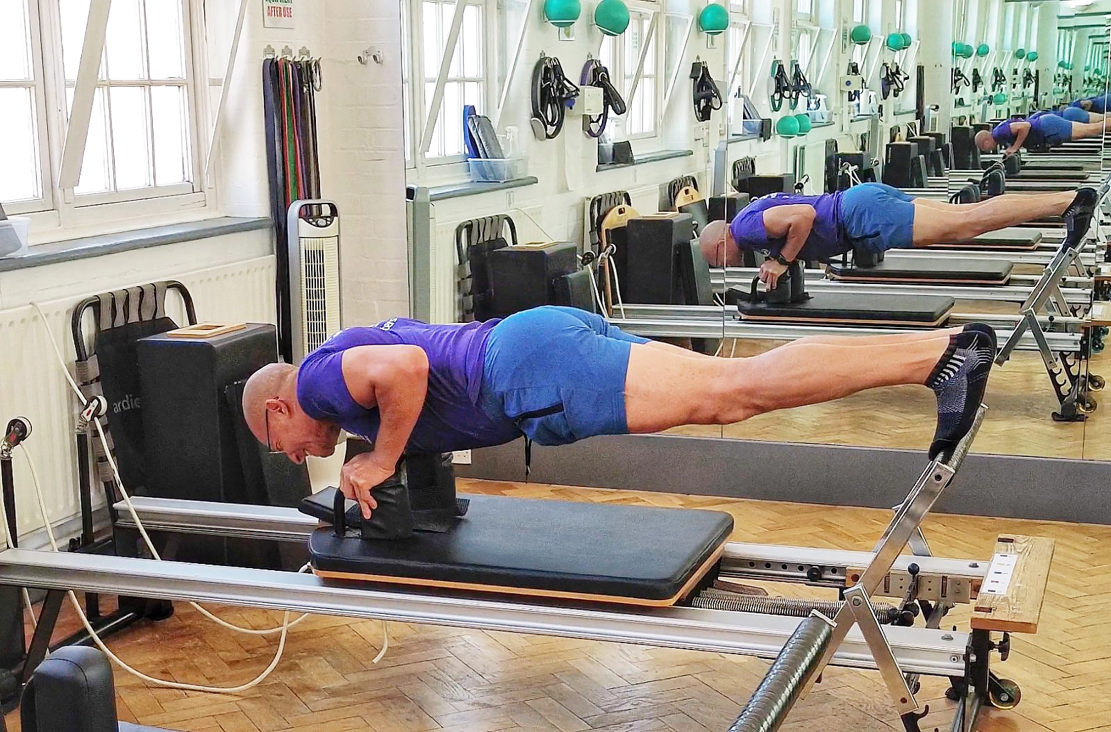 Teejay Sogunro performing reverse plank press-ups on the Reformer at The Sogunro Practice, London Colney, St Albans